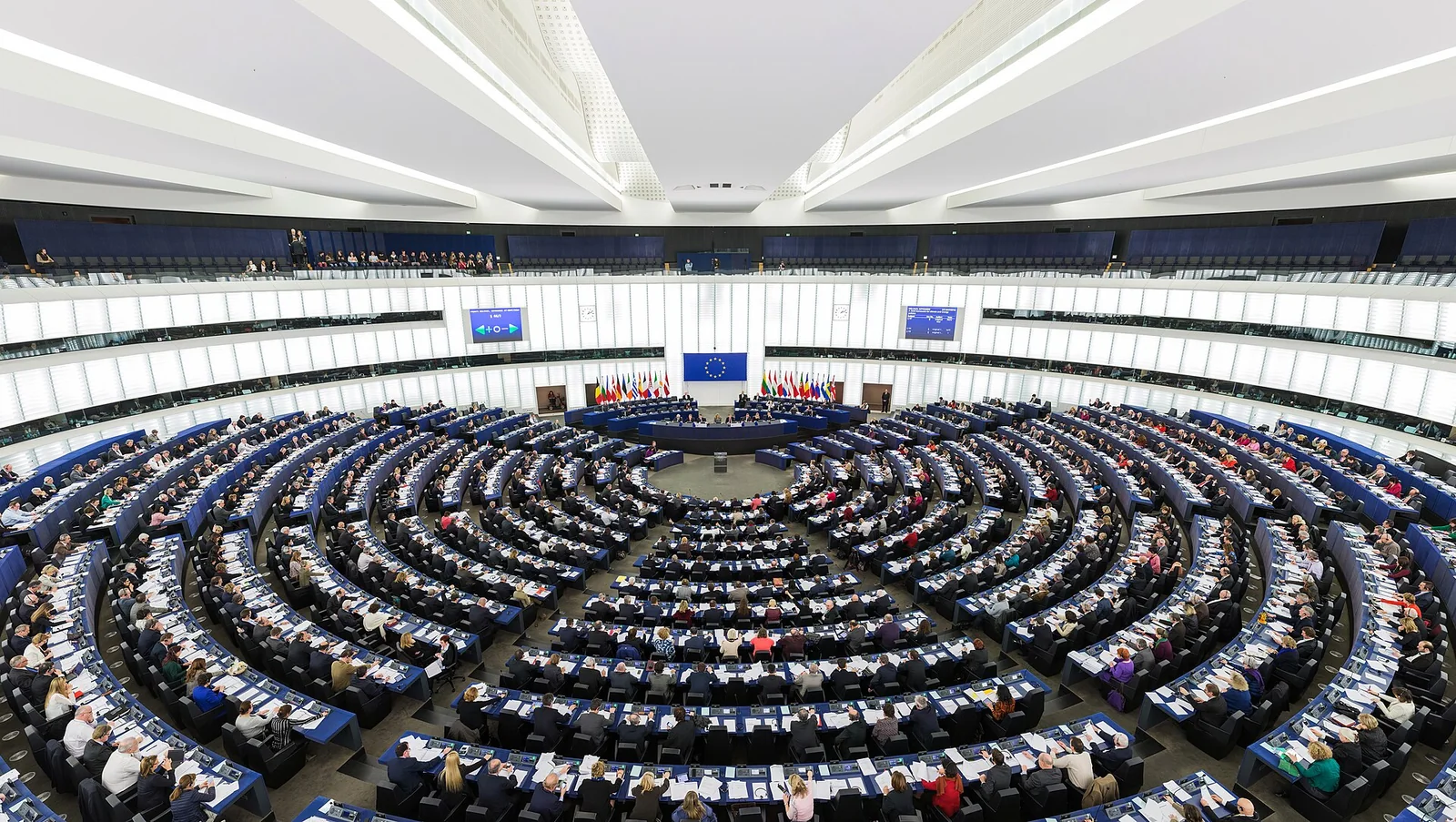 L'emiciclo del Parlamento europeo a Strasburgo: ampia sala semicircolare con file curve di banchi e scranni che digradano verso il podio centrale.