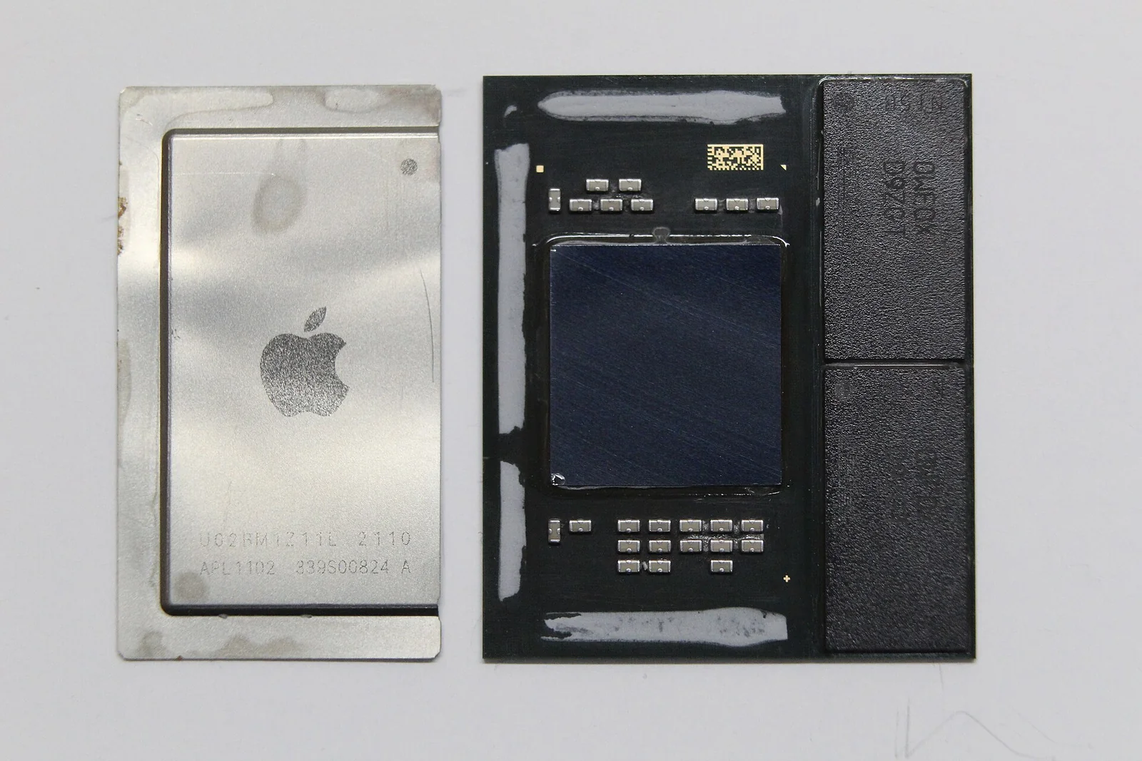 Primo piano del chip Apple M1 con il dissipatore integrato rimosso: si vede il die di silicio quadrato al centro del package e i due moduli di memoria affiancati sul substrato.