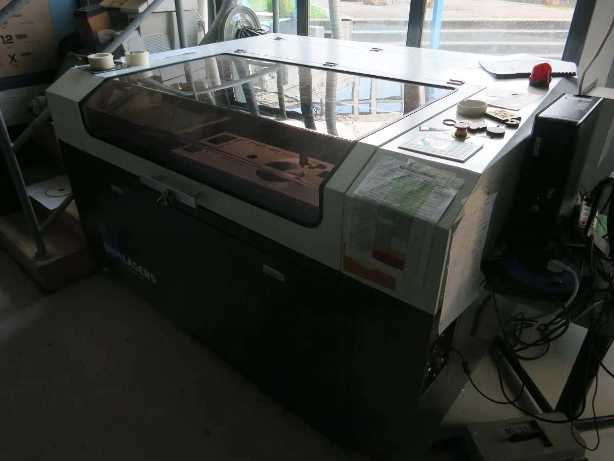Una macchina da taglio laser in un fab lab, con piano di lavoro e testa di taglio motorizzata sotto il coperchio trasparente.