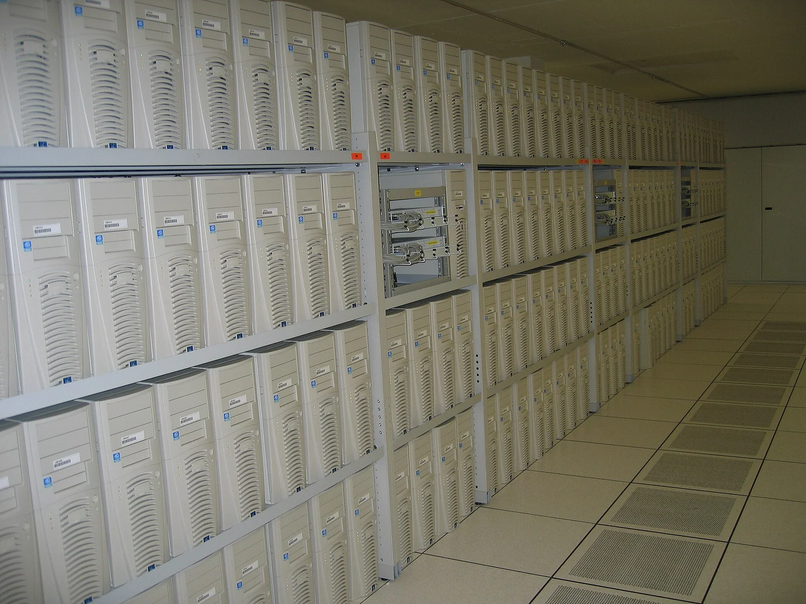 Fila di armadi rack pieni di server e cavi nel centro di calcolo del CERN, parte della griglia di calcolo scientifica.