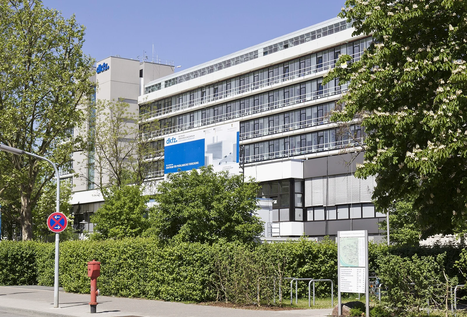 Edificio moderno del Deutsches Krebsforschungszentrum (DKFZ) a Heidelberg sotto un cielo limpido, con facciata a fasce orizzontali.