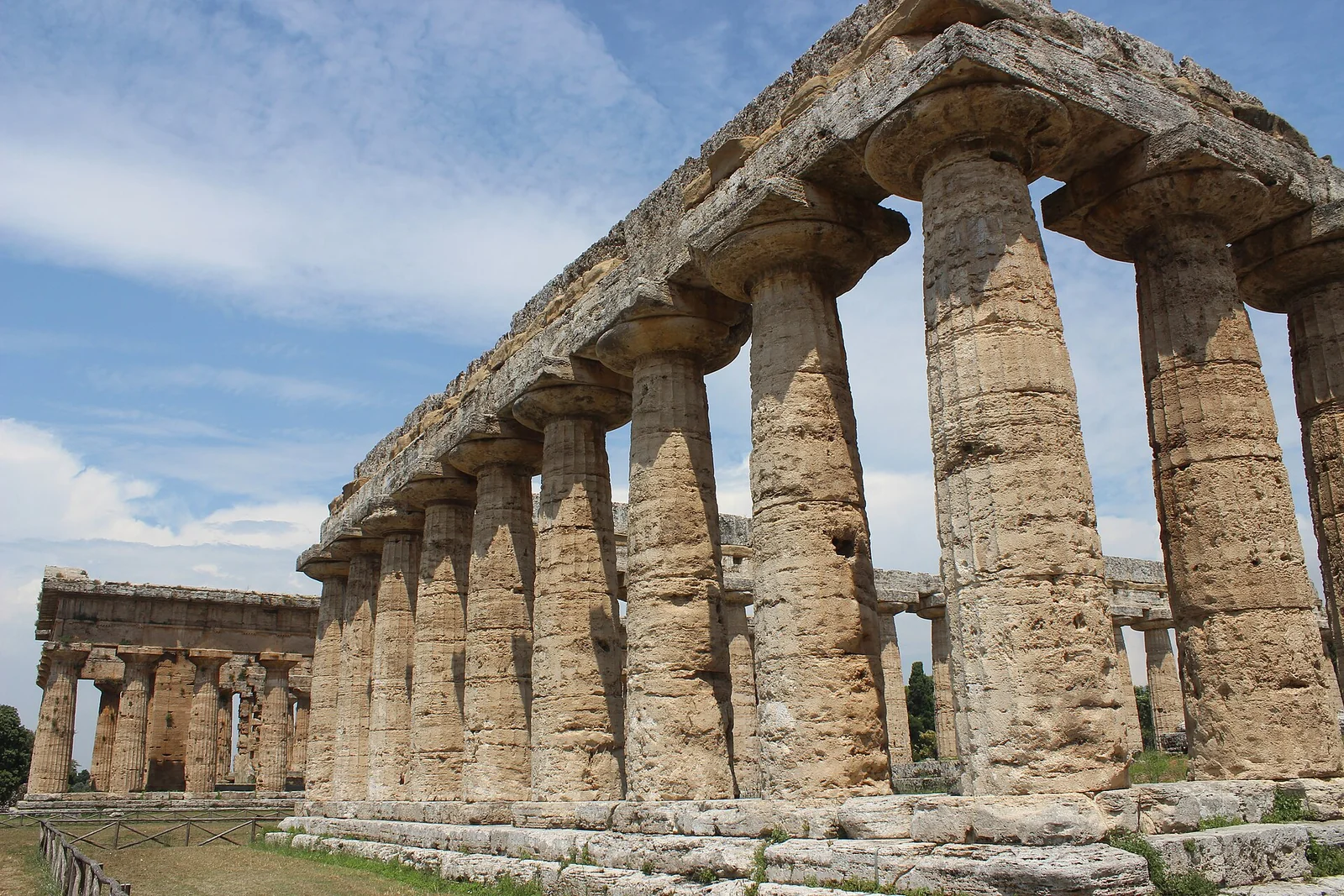 I templi dorici greci di Paestum visti dal sito archeologico: due grandi templi in pietra calcarea color ocra con colonne intatte, sotto un cielo limpido.