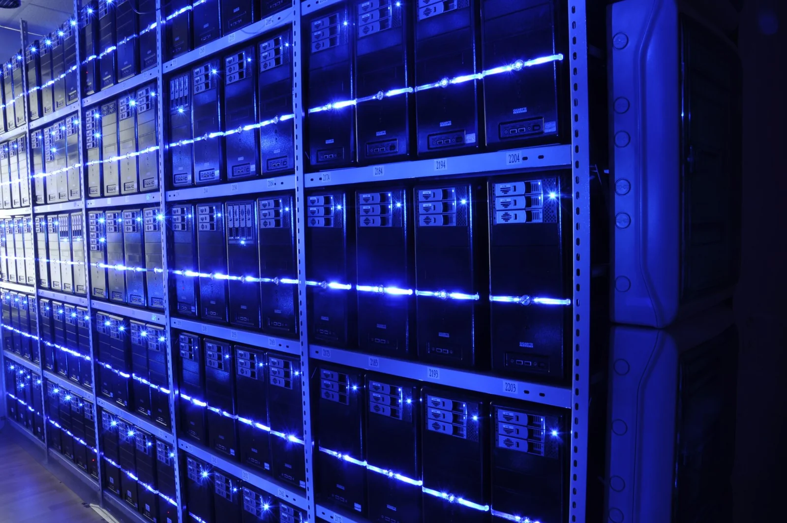 Interno di un data center con file di rack di server illuminati in una sala macchine