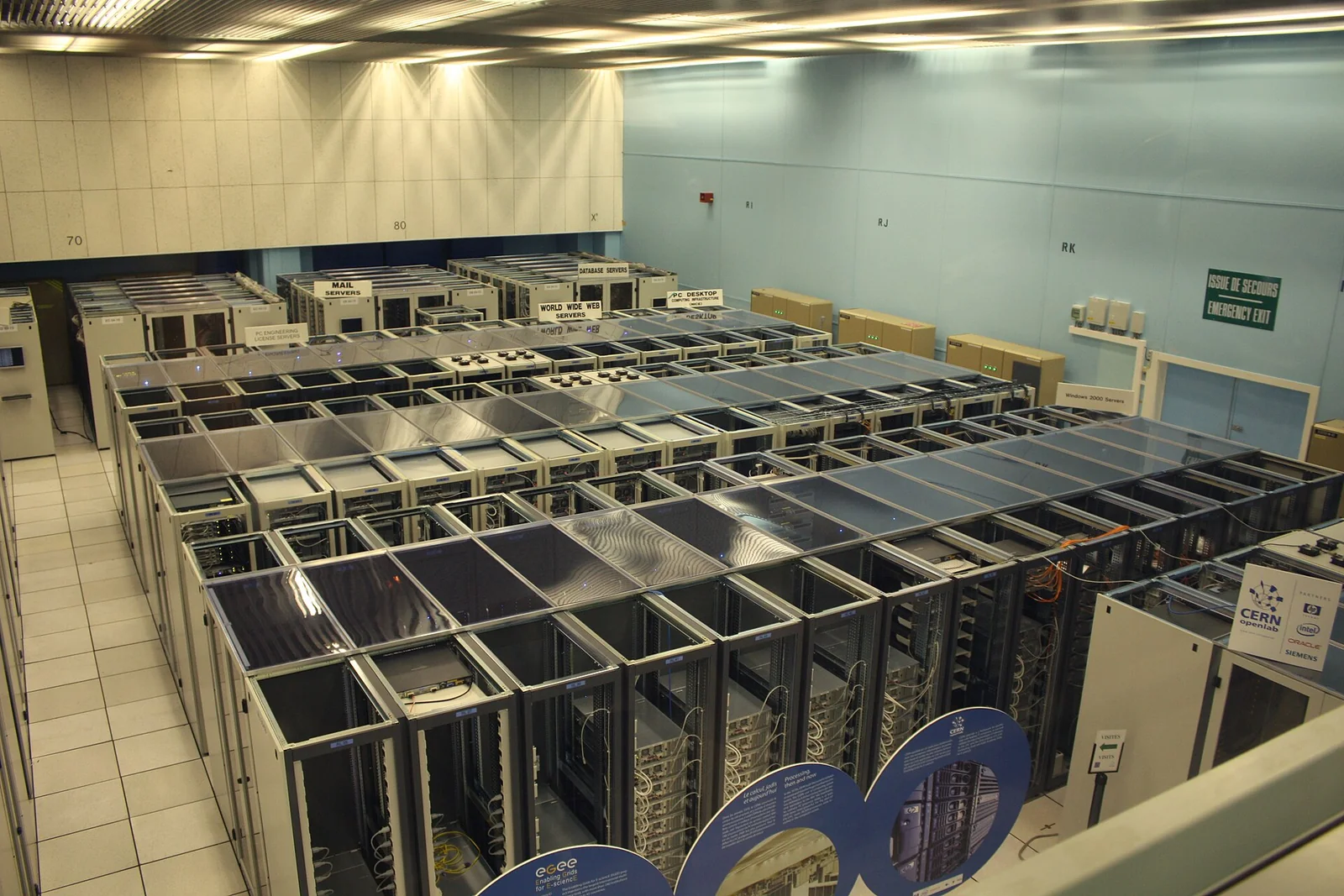 File di armadi rack pieni di server in una sala data center, con cavi e apparecchiature di rete in vista.