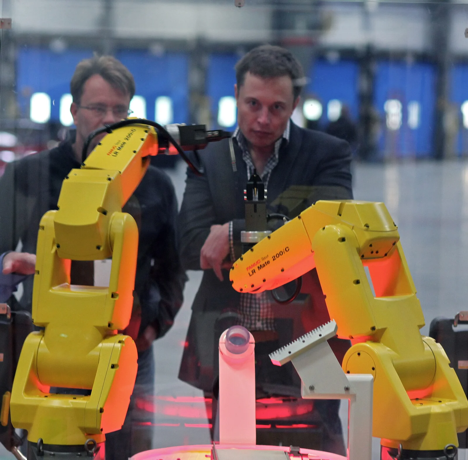 Bracci robotici industriali gialli FANUC al lavoro in una linea di assemblaggio di una fabbrica.
